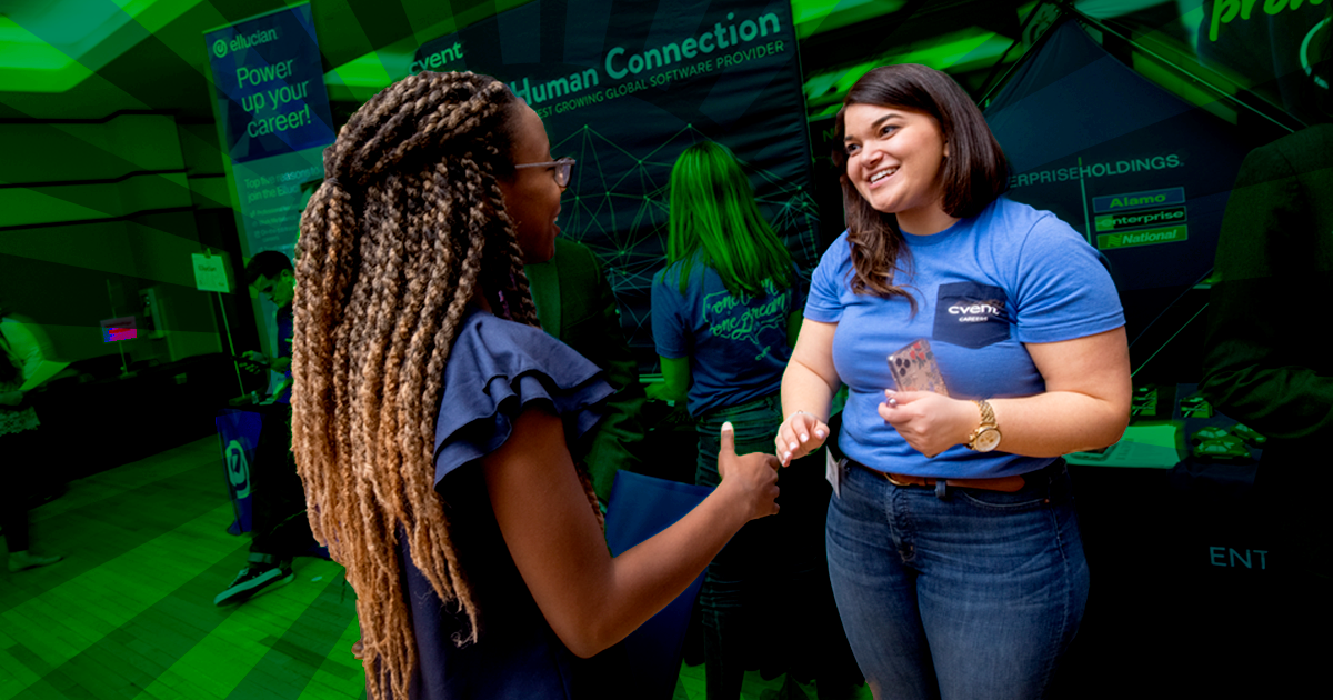 Two women attending a previous Career Fair at Mason. They are wearing blue and shaking hands.